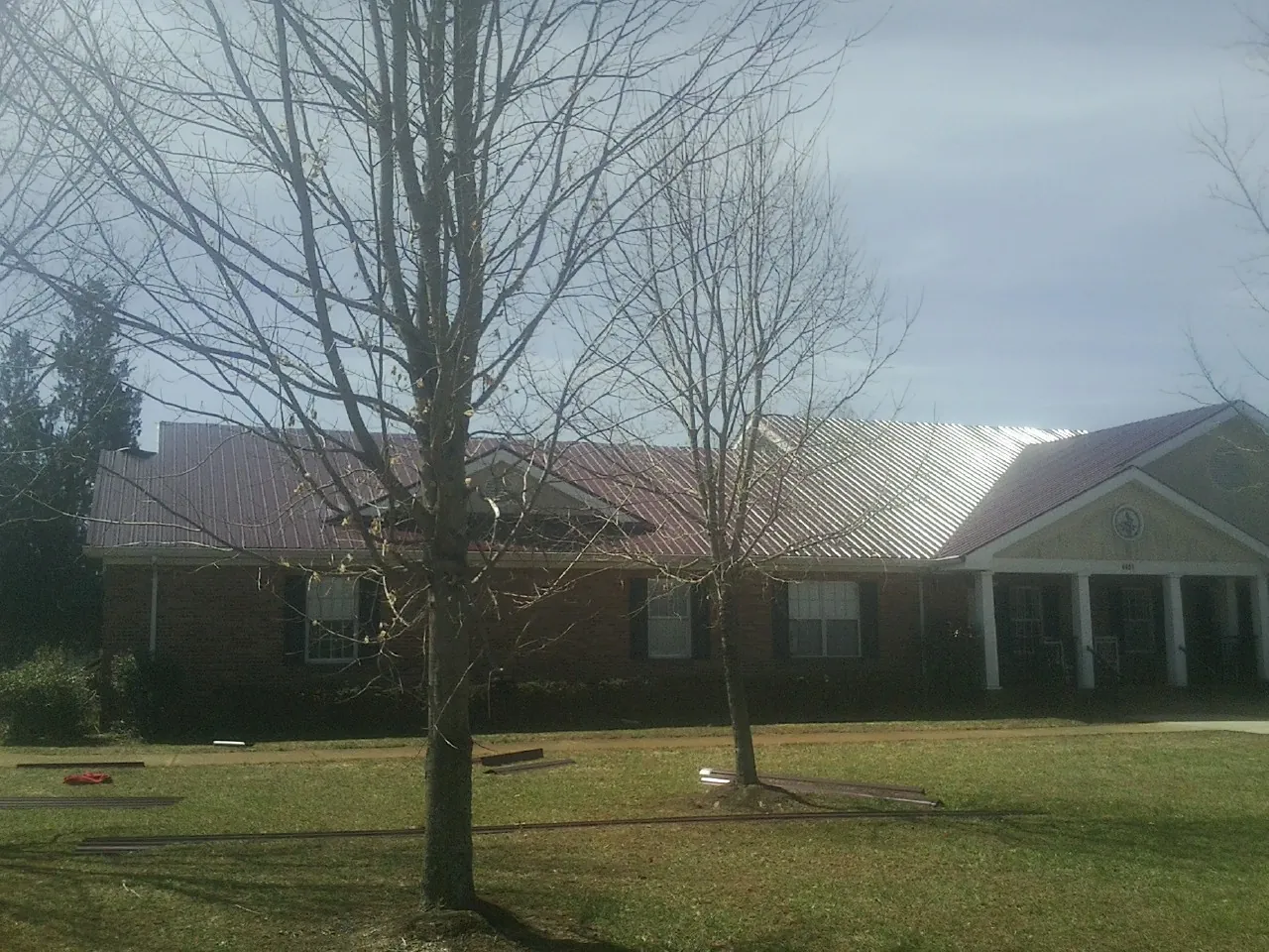 Red metal roof on a brick building seen from the front lawn in Martville