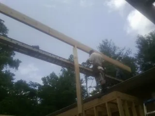 Carpenter setting a ridge beam over a new addition frame — Ice Dam Removal by Roofing Brothers in Martville