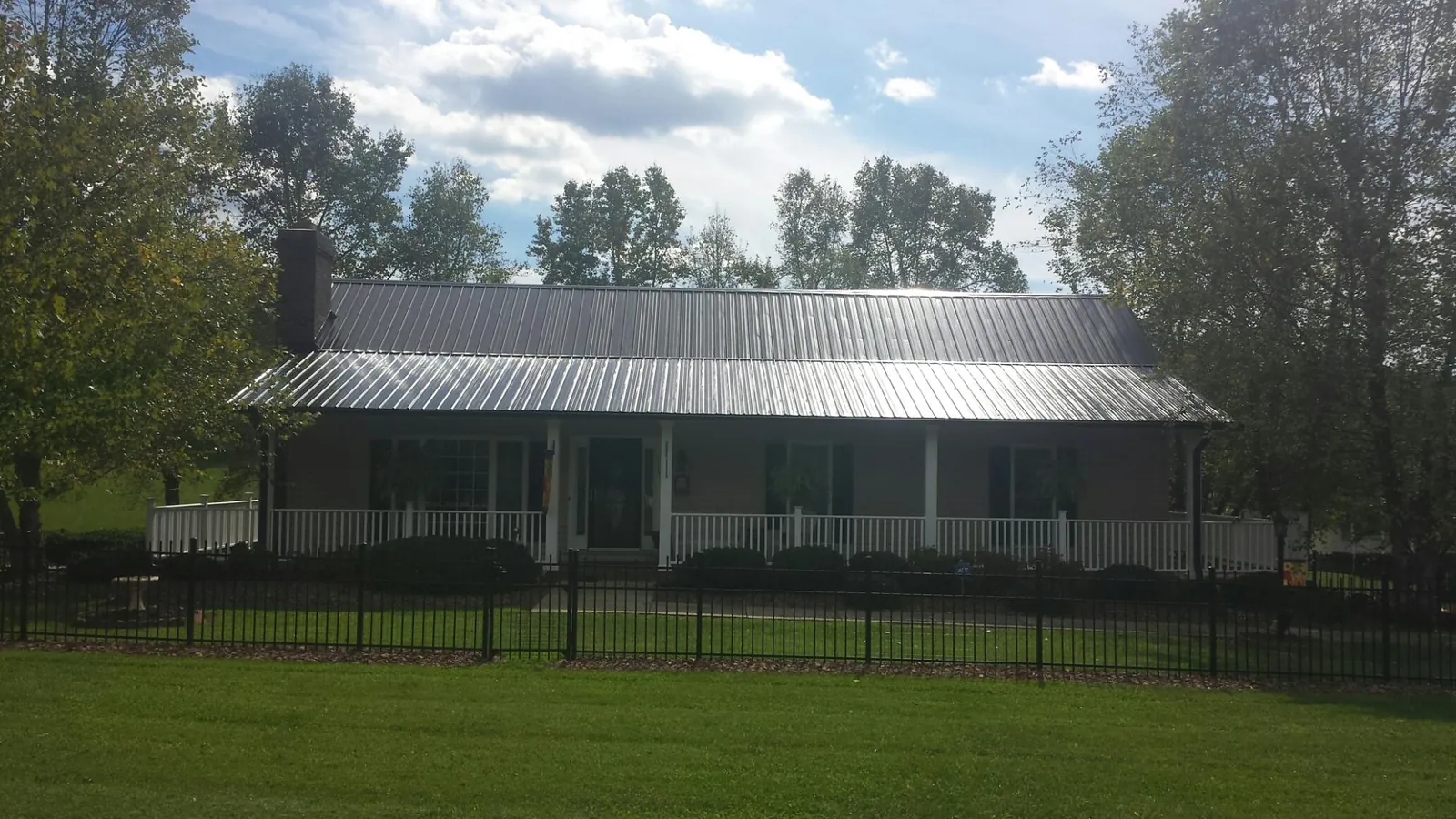 Gray metal roof on a brick ranch with a full width front porch — Gutter Guard Installation work by our crew in Martville