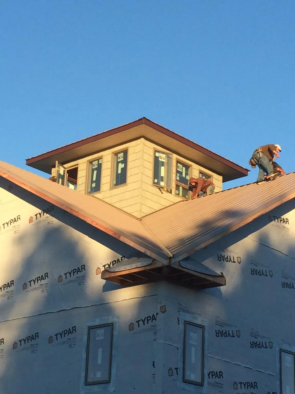 Roofers working around a rooftop cupola on a new metal roof at sunset — Roof Waterproofing in Martville by Roofing Brothers